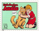 on this U.S. postage stamp, Annie, in a red dress and on her knees, huggs her orange dog, Sandy