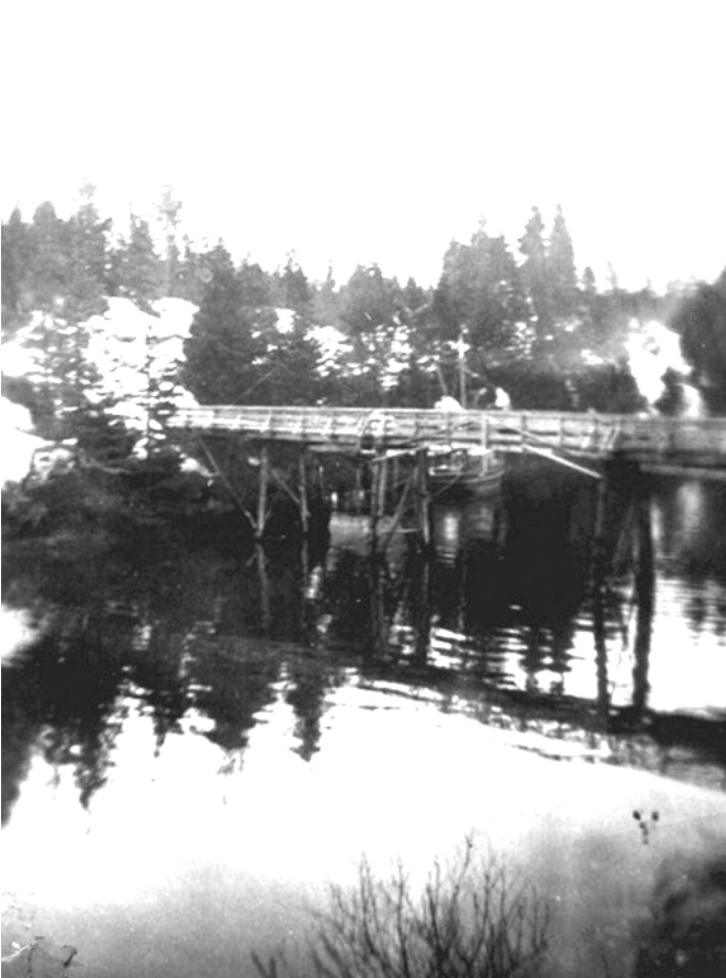 Wooden bridge over the slough, a snowy hillside above it