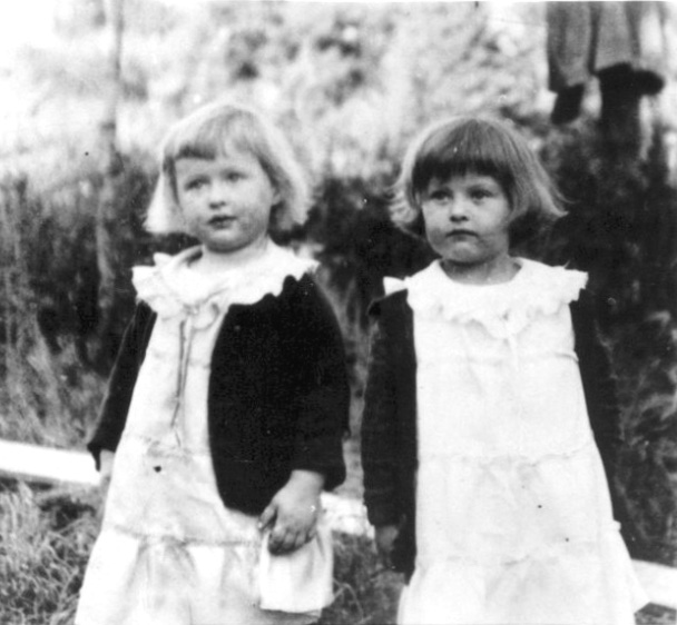 Two small girls in dresses with lace collars and dark sweaters