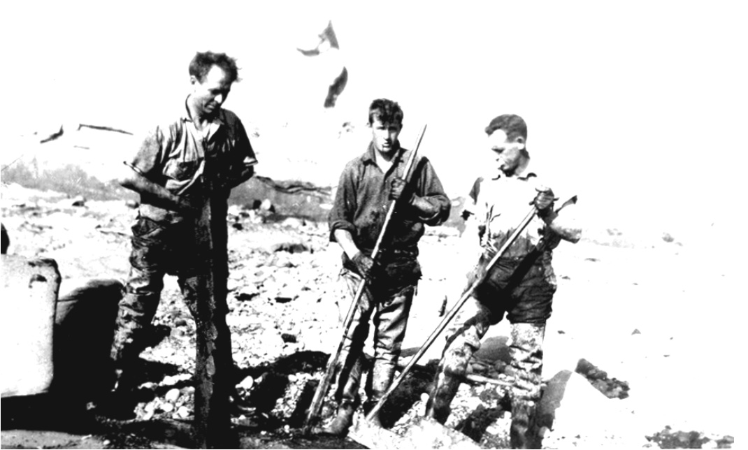 Three men with crowbars, prying coal from the beach