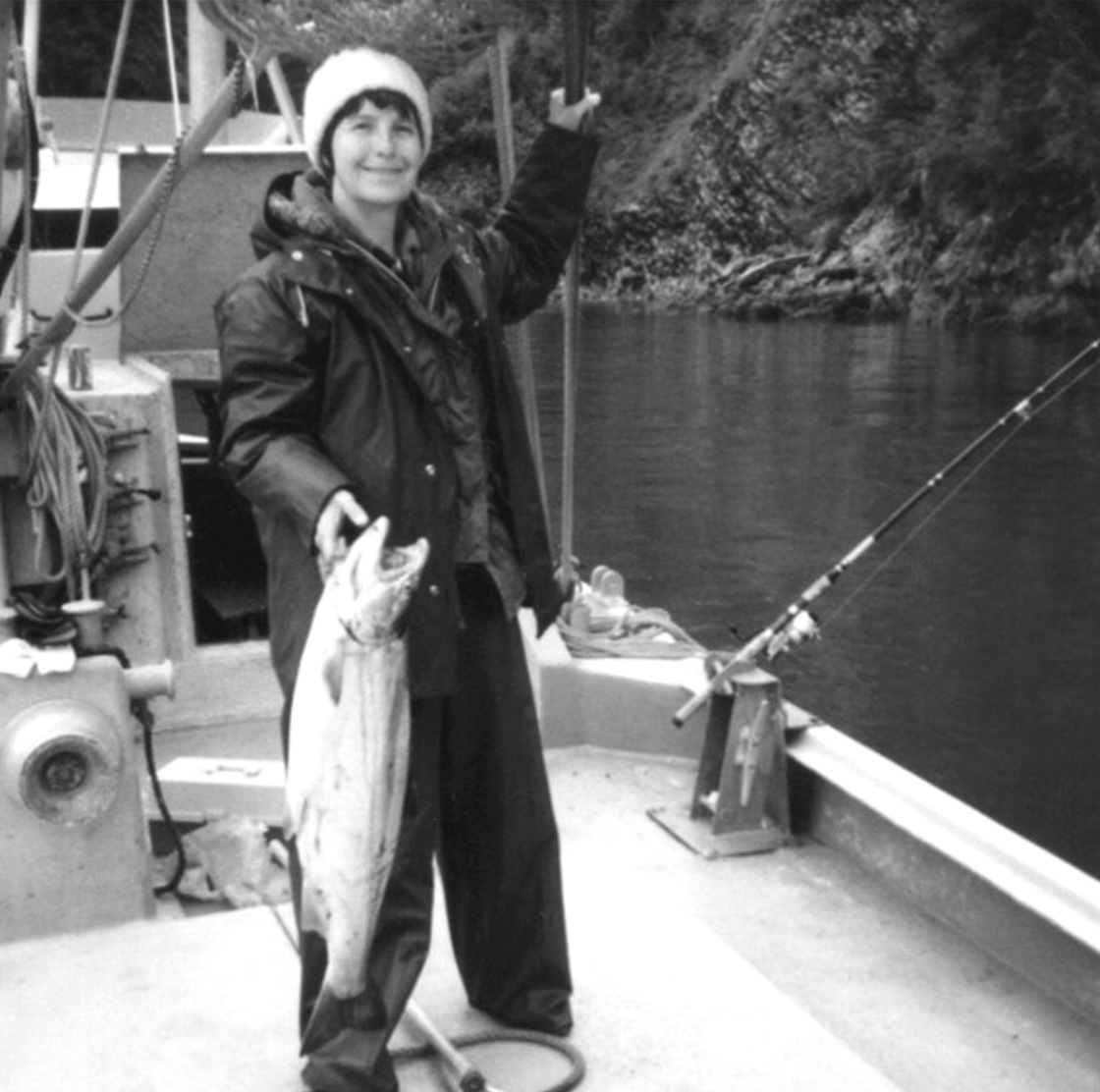 The author on a fishing boat holding a large salmon with her right hand.