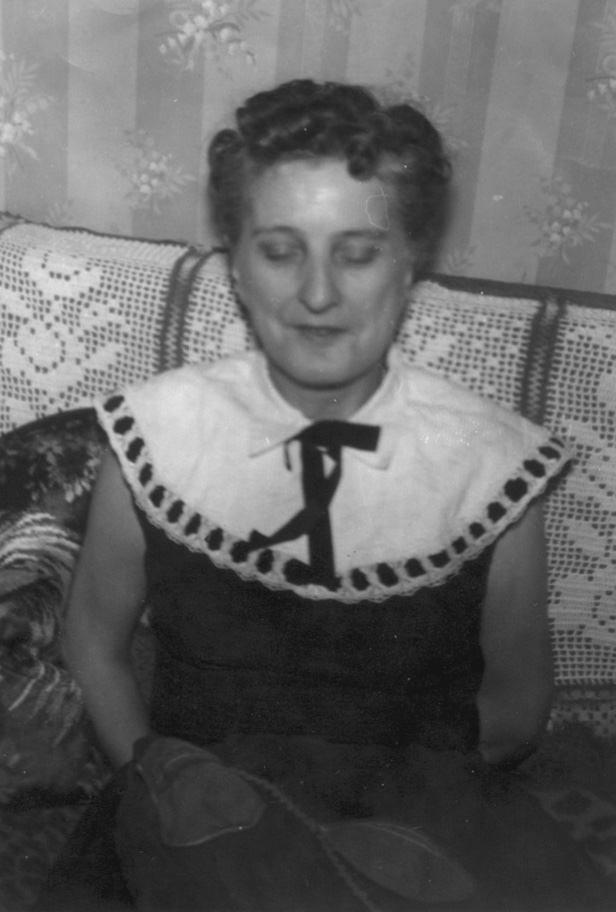 Woman with her eyes closed sitting on a couch, wearing a dress