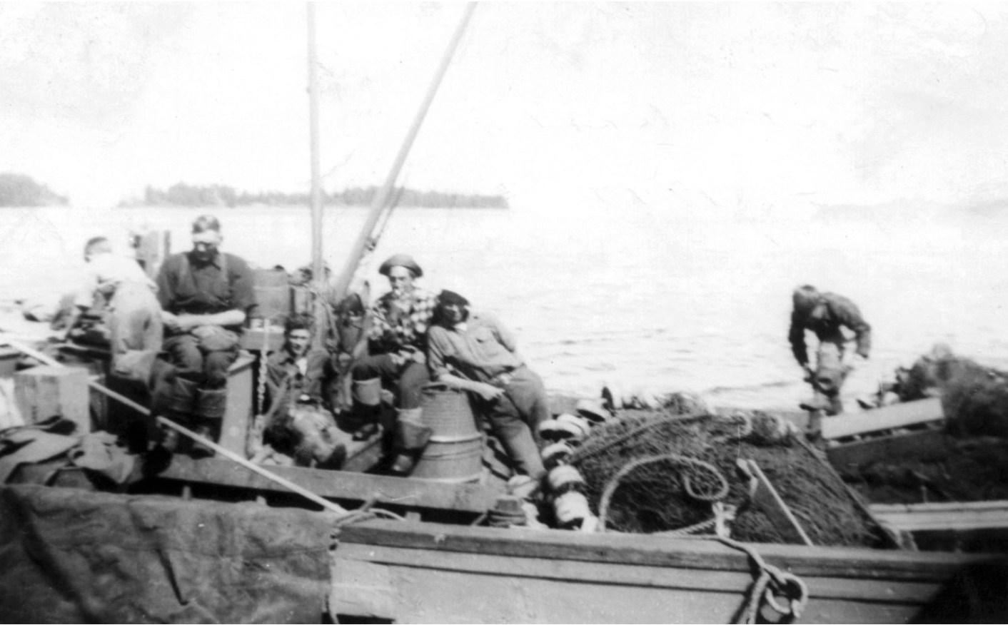 Deck of a boat with five men, nets, and other equipment