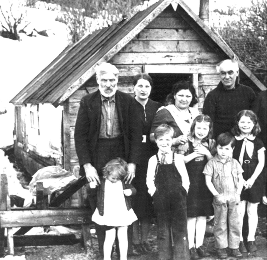 Grandfather with family before a wooden shack; his hands on Dolly's shoulders, behind him the author's mother, to his left Aunt Sue and Uncle Rufas, to the left of Dolly, Tom, Mae (the author), Sonny, and Deloris