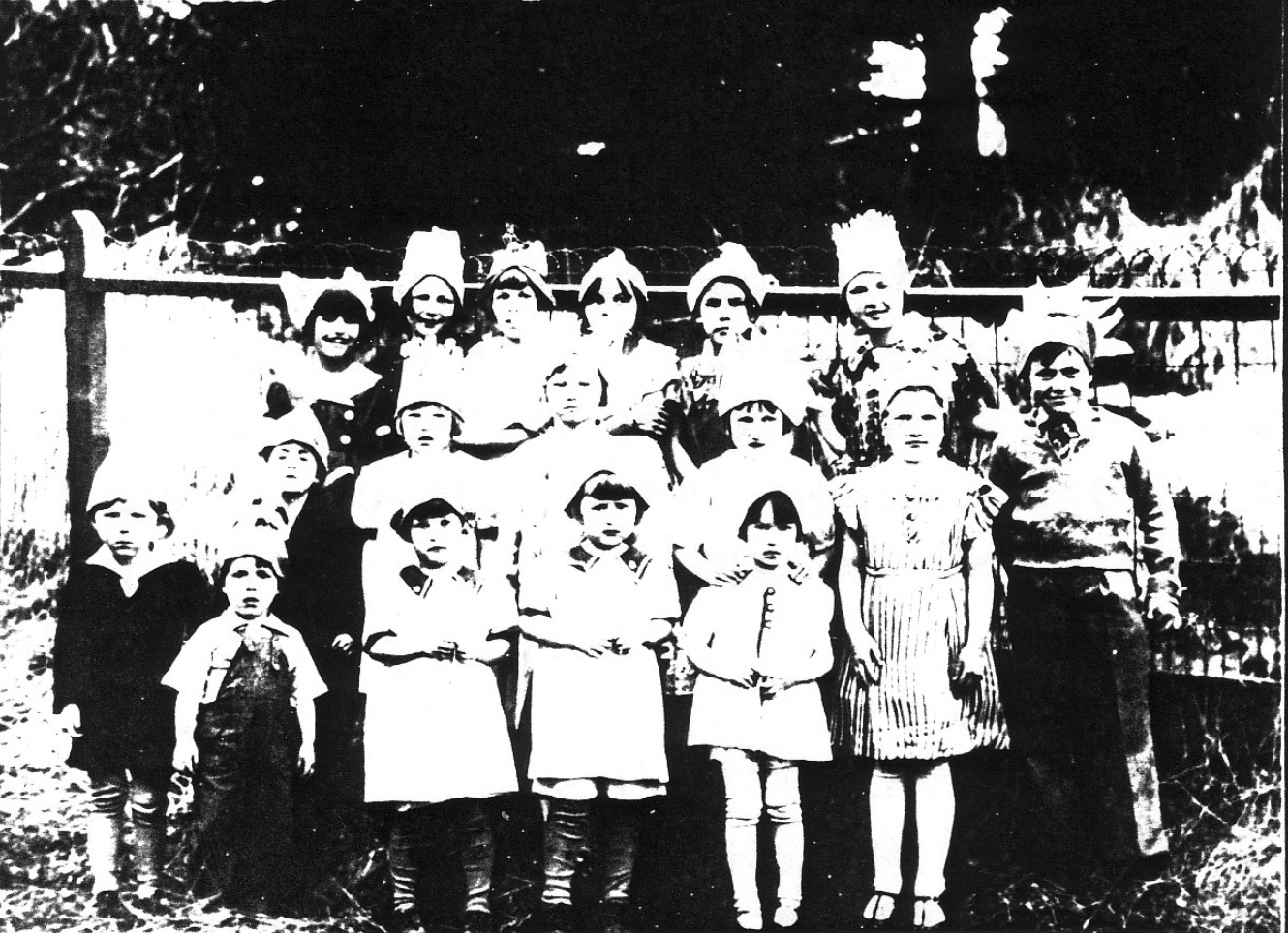 Seventeen children in three rows wearing party hats
