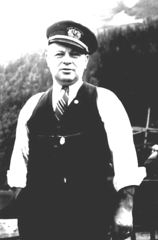 Man in white shirt, vest, and tie wearing a captain’s hat