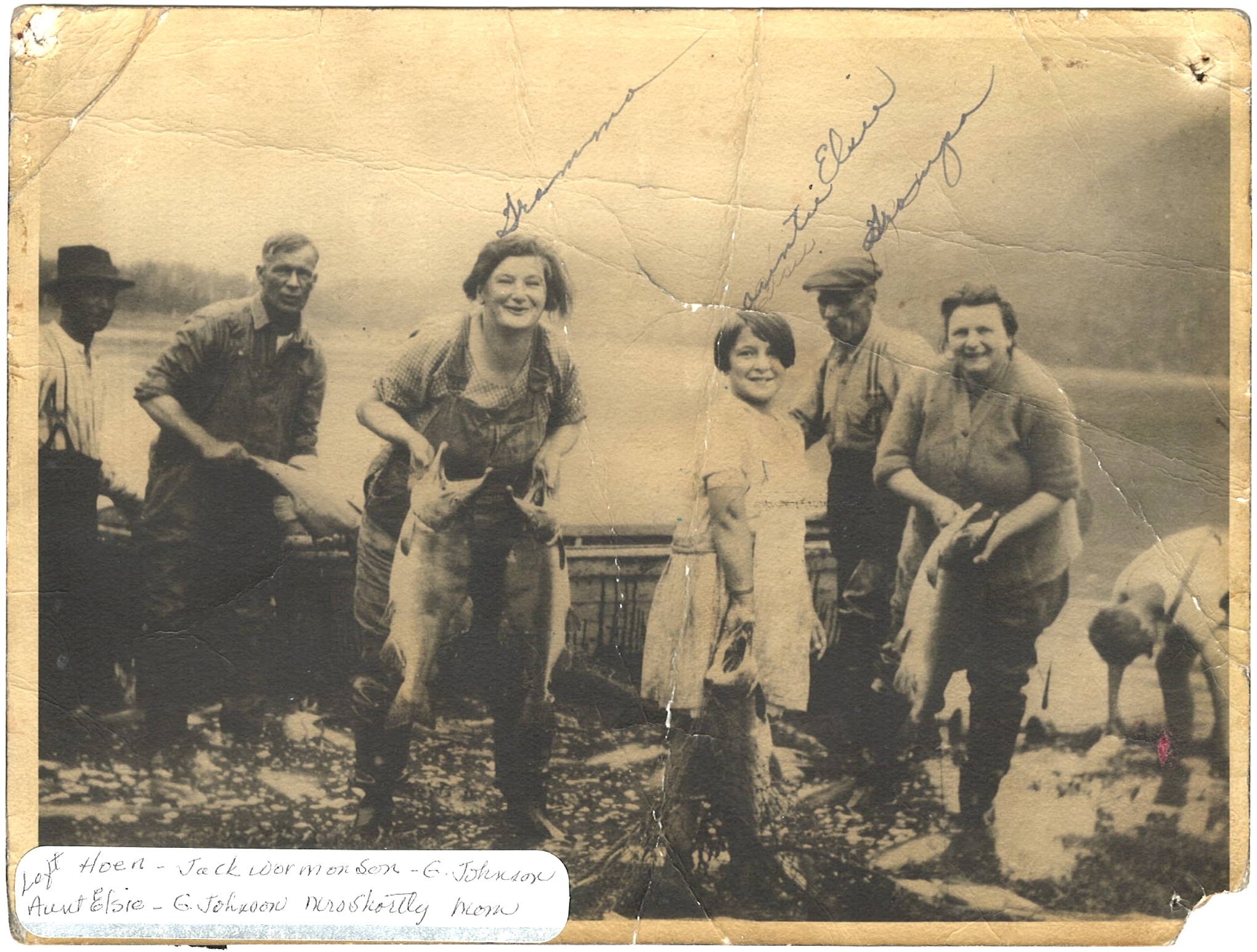 People standing on a beach before a dory holding large salmon by their gills