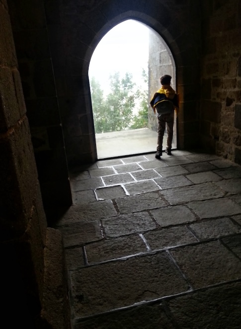 A boy dances in an almonry window in the Merveille at Mont Saint-Michel